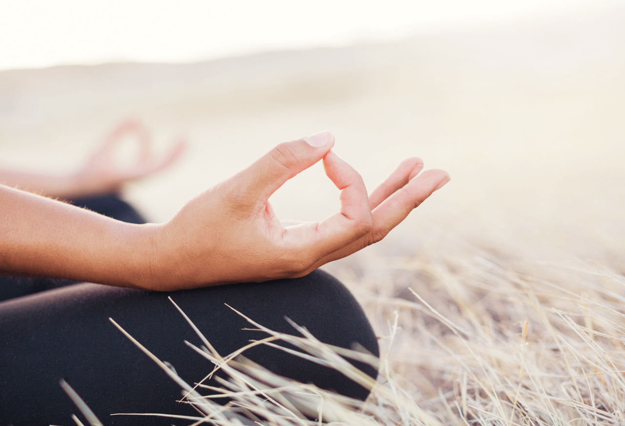 Hand in meditativem Mudra während einer Yoga-Session in der Natur – entspannende Atmosphäre für Yoga-Reisen, Achtsamkeit, innere Ruhe und ganzheitliche Erholung.